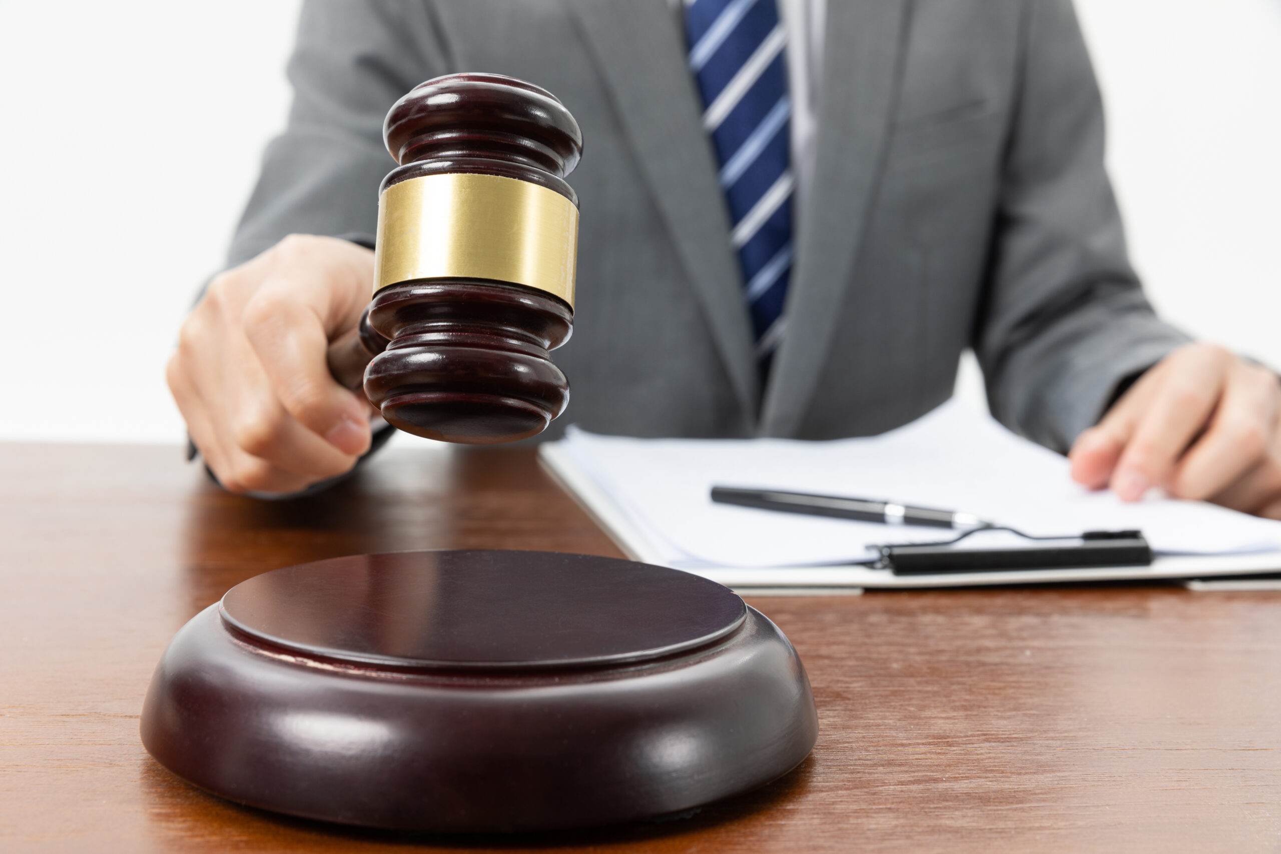 A closeup shot of a person with a gavel in hand and papers on the table